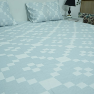 Light powder blue and white geometric pixel pattern bed sheet set on a bed with a white headboard