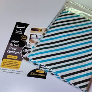 White bed sheet set with bold black and electric blue diagonal stripes folded in packaging